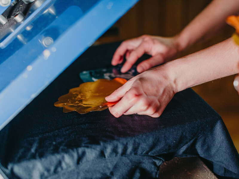 Close up of hands using a screen printing machine